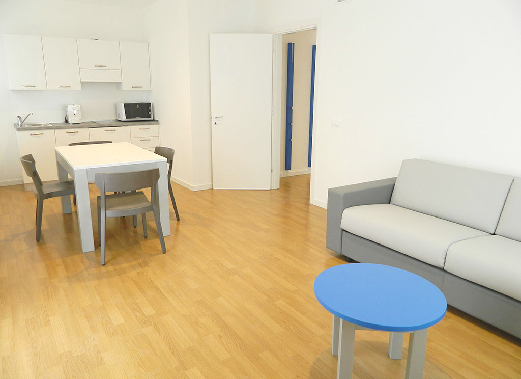 Living area with kitchenette and sofa of the Deluxe 60 sqm apartment, Palamostre Residence, Udine