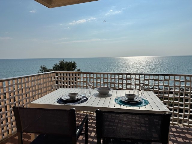 Seafront terrace with dining table and view over the open sea of Grado