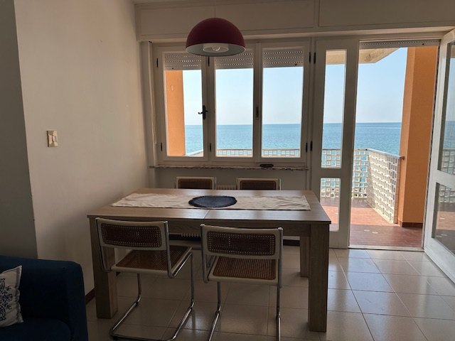 Dining area of the apartment with sea view through the large windows, Grado