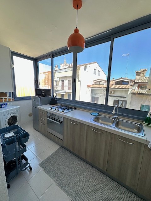 Bright kitchen with large window overlooking the sea and rooftops of Grado