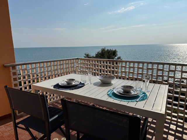 Tavolo apparecchiato sulla terrazza dell'appartamento di Grado con vista aperta sul mare azzurro
